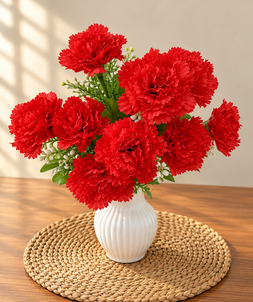 Artificial red carnation bouquet in white ribbed vase on woven mat