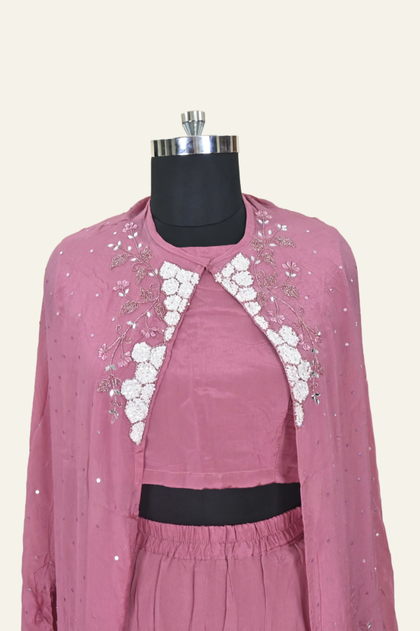 Butter Crepe suit set comprising a cape jacket with floral motifs, a flared leg pant and a blouse. Embellishments include sequins, Cutdana and Dabka work