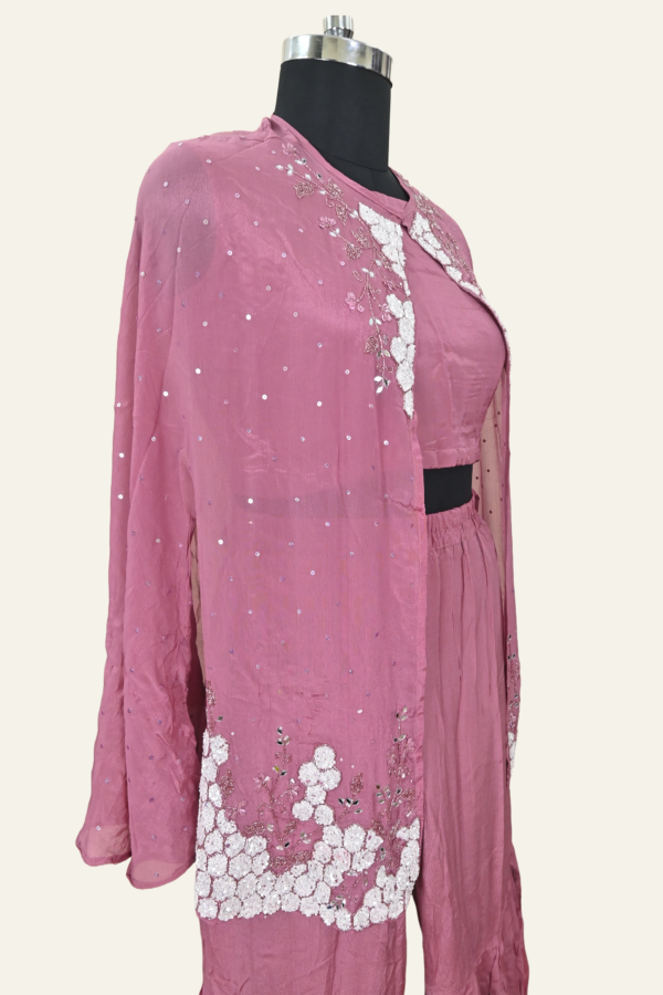 Butter Crepe suit set comprising a cape jacket with floral motifs, a flared leg pant and a blouse. Embellishments include sequins, Cutdana and Dabka work