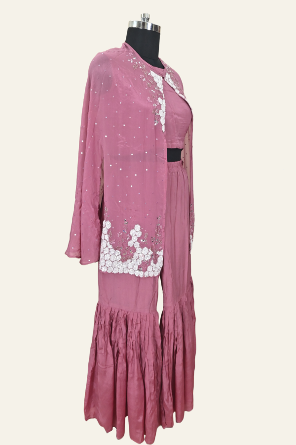 Butter Crepe suit set comprising a cape jacket with floral motifs, a flared leg pant and a blouse. Embellishments include sequins, Cutdana and Dabka work